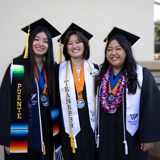 Three graduates waving at camera